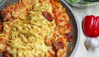 pan of cajun shrimp and sausage pasta with salad