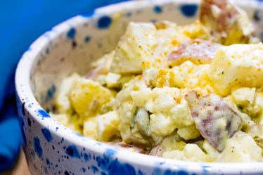 White bowl with blue specs filled with southern style potato salad.