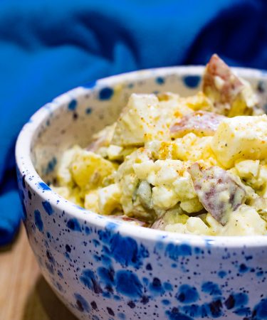 White bowl with blue specs filled with southern style potato salad.