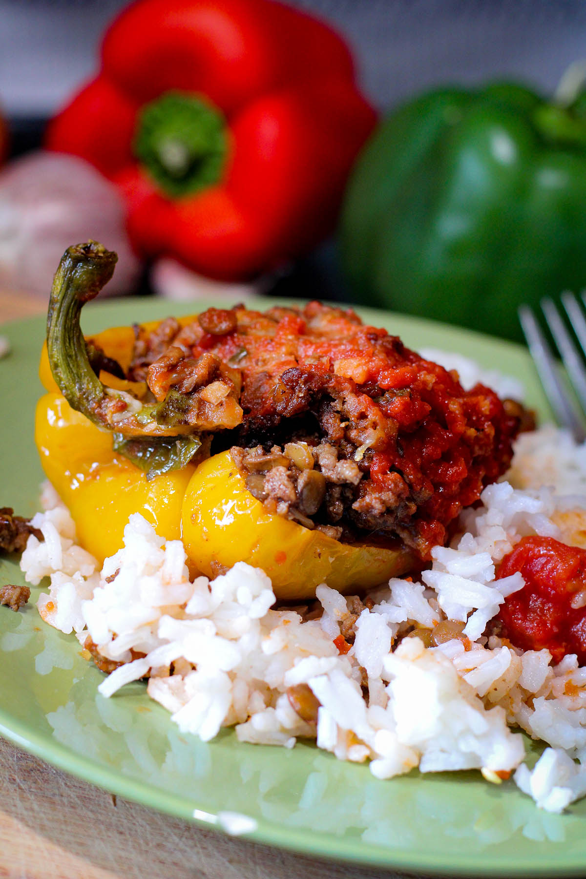 Half a yellow stuffed bell pepper topped with sauce and served over white rice.