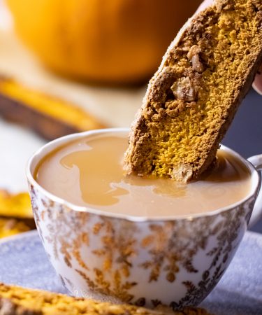 Pumpkin biscotti being dunked into a cup of tea.