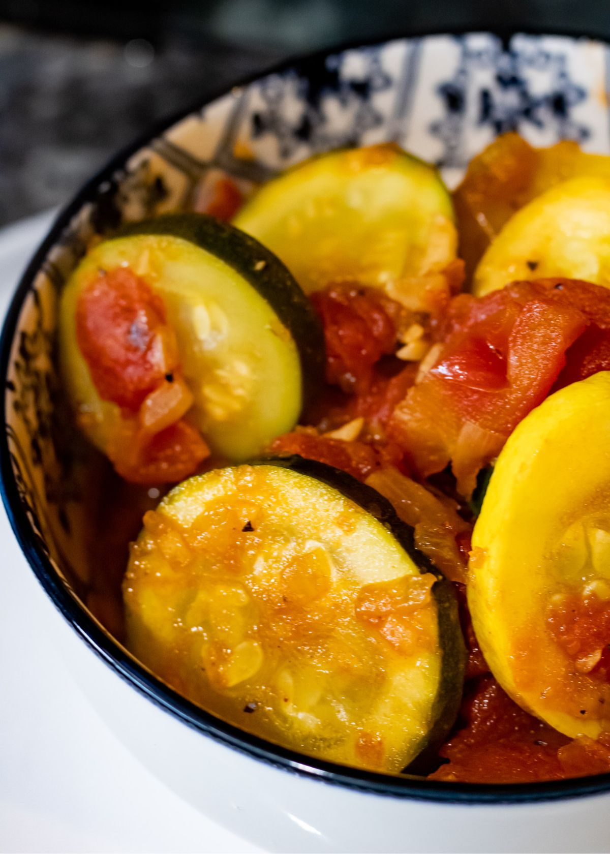 Side close shot of squash and tomatoes in a bowl.