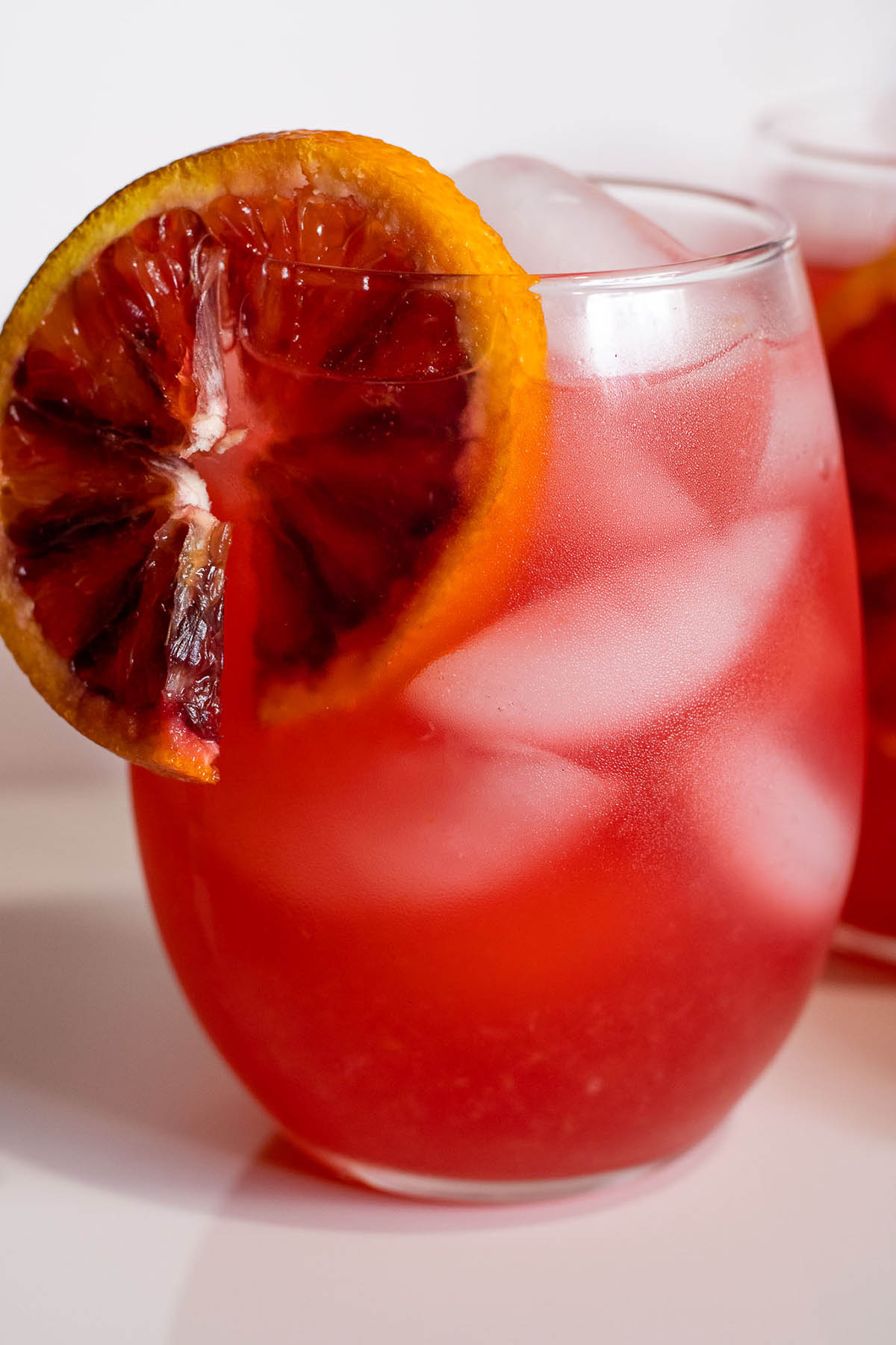 Glass of blood orange lemonade with a slice on the rim.