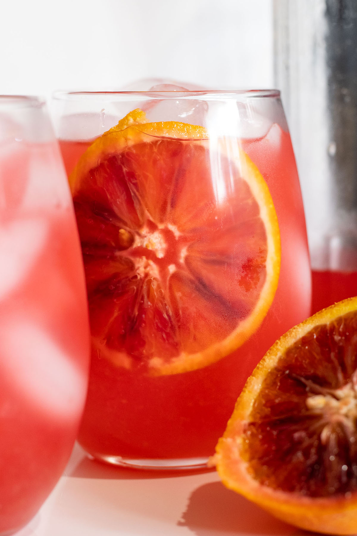 Close up of a slice of citrus inside a glass with a orangish red color.