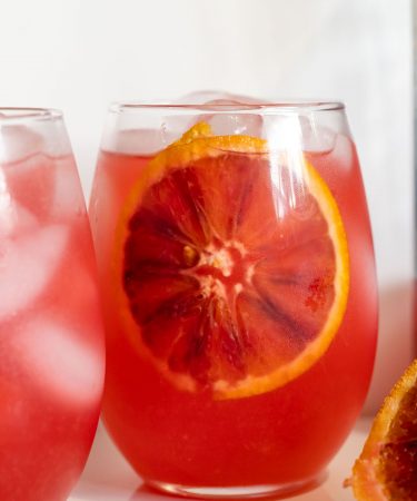 Crisp and refreshing blood orange lemonade with a slice dipped in.