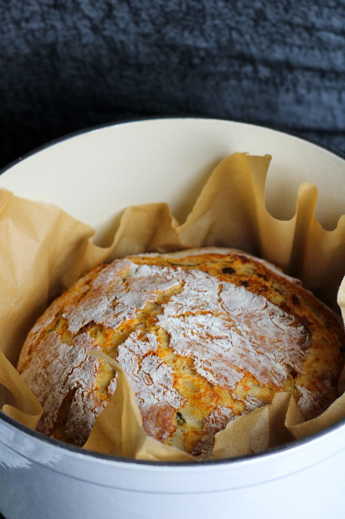 Jalapeno cheddar bacon bread in a parchment lined Dutch oven.