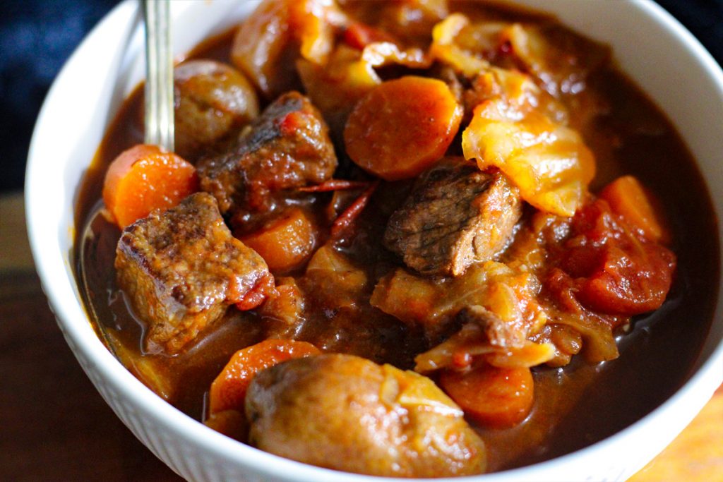 Bowl of tender beef and cabbage soup with potatoes and carrots.