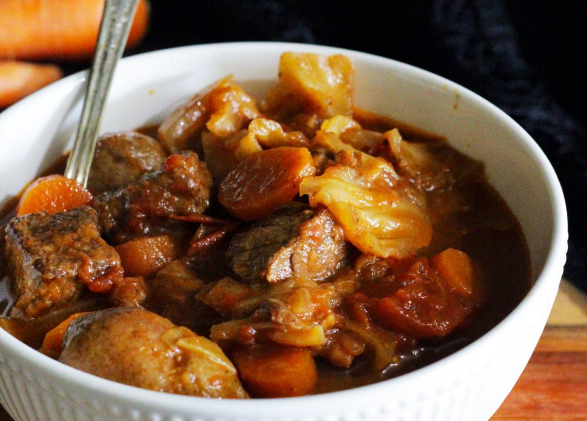 Bowl of cabbage soup with beef, carrots and tomatoes.