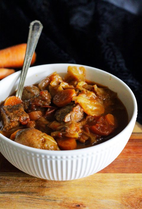 Bowl of cabbage soup with beef, carrots and tomatoes.
