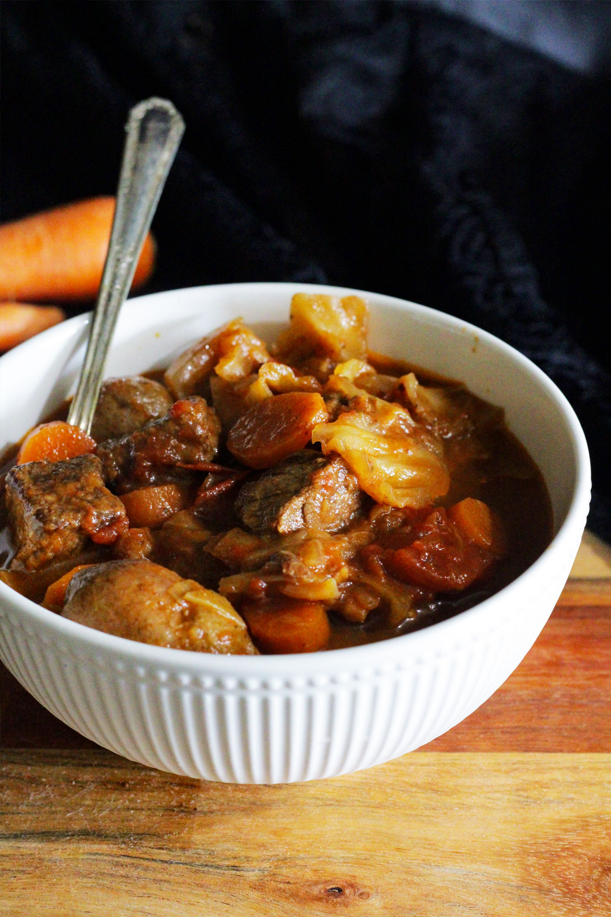 Bowl of cabbage soup with beef, carrots and tomatoes.